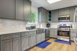 A modern kitchen with grey cabinets, stainless steel appliances, and a window providing natural light. - Private Patio & Yard! Bastrop Retreat (Bastrop)
