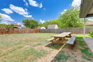 A backyard with a wooden picnic table, a wooden fence, and houses in the background. - Private Patio & Yard! Bastrop Retreat (Bastrop)