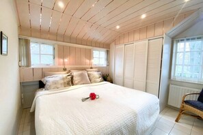 Ein Schlafzimmer mit einem großen Bett, einem Fenster, einer Heizung und einem Sessel.