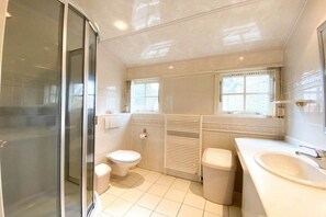 Ein Badezimmer mit Duschkabine aus Glas, Toilette, Bidet und Waschbecken.