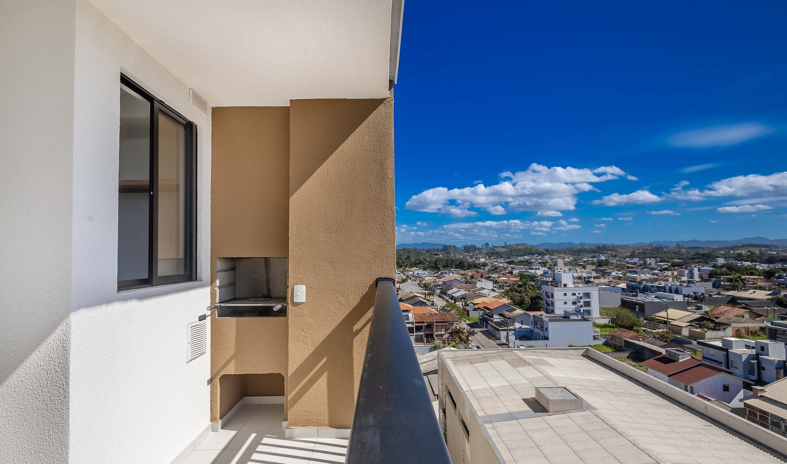 Un balcó amb vista a una zona residencial i muntanyes llunyanes.