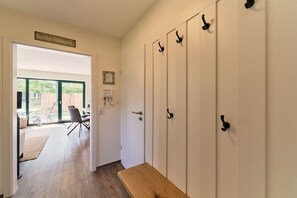 A hallway with a bench, a door with a sign, and a view into a room with a table and chairs. - Holiday apartment with 2 bedrooms (Wittmund)
