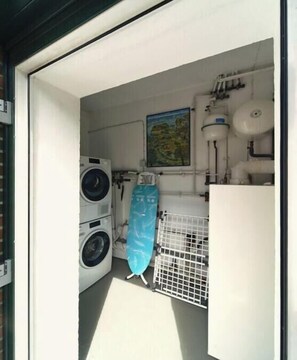 A laundry room with a washing machine, drying rack, ironing board, and a water heater. - Holiday apartment with 2 bedrooms (Wittmund)