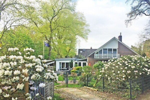 Il s’agit d’une propriété résidentielle comprenant une maison, un patio couvert et un jardin agrémenté de plantes à fleurs.
