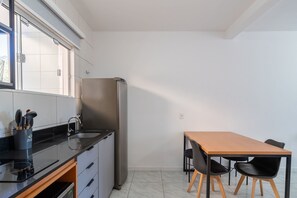 Eine kompakte Küche mit Kühlschrank, Spüle und einem Essbereich mit Tisch und Stühlen.