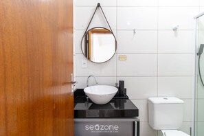 A bathroom with a white sink, a mirror, a toilet, and a wall-mounted towel rack. - Comfortable Vacation apt in Jurere Jma006 (Florianópolis)