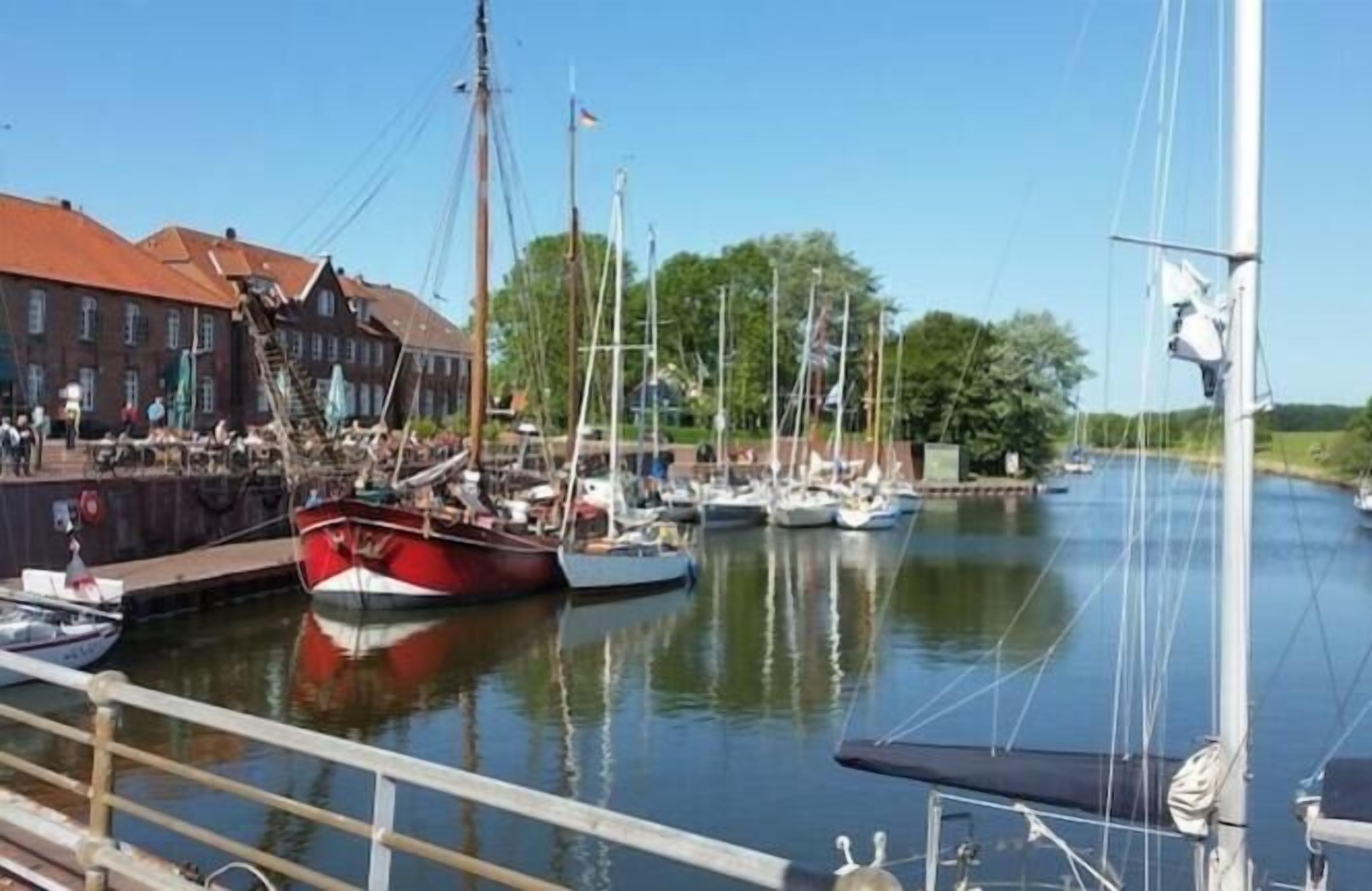 A marina with boats docked, a building with a red roof, and a clear sky.