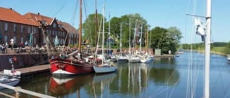 A marina with boats docked, a building with a red roof, and a clear sky.