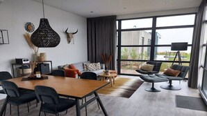 Ein modernes Wohnzimmer mit Essbereich, großen Fenstern und Blick ins Freie.
