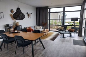 Una sala de estar moderna con comedor, ventanas grandes y vistas al exterior.