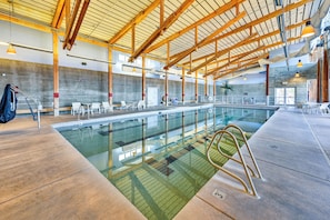 An indoor swimming pool with a high ceiling, concrete walls, and multiple seating areas. - Golf Views, Resort Pool Access! Brasada Ranch Home (Powell Butte)