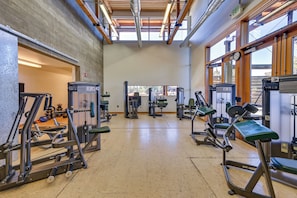 A gym with various exercise machines, a concrete wall, and large windows allowing natural light. - Golf Views, Resort Pool Access! Brasada Ranch Home (Powell Butte)