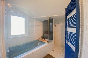 A bathroom with a bathtub, a window, and a shower area. - DO10 Apartment in the center of Domburg (Domburg)