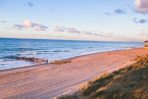 A beach with a wooden jetty, sandy shore, and a building in the background. - DO10 Apartment in the center of Domburg (Domburg)