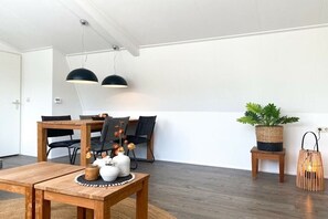 A dining area with a wooden table and chairs, pendant lights, a potted plant, and a small stool. - DO10 Apartment in the center of Domburg (Domburg)