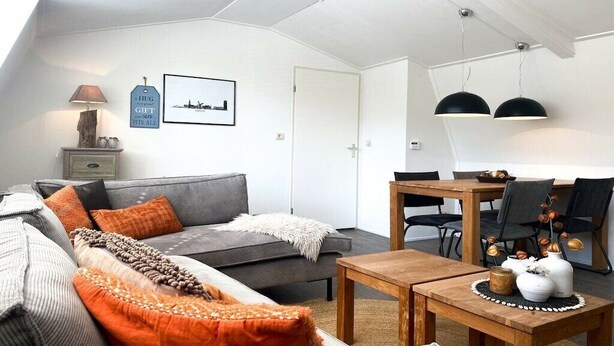 Un salon moderne avec un canapé gris, une table basse en bois et un coin repas comprenant une table et des chaises en bois.