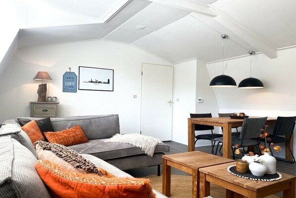 A modern living room with a grey sofa, wooden coffee table, and a dining area with a wooden table and chairs. - DO10 Apartment in the center of Domburg (Domburg)