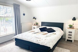 A bedroom with a bed, bedside lamps, a window with curtains, and a radiator. - DO10 Apartment in the center of Domburg (Domburg)