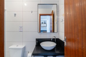 A bathroom with a white toilet, a black sink with a vessel basin, and a mirror above the sink. - Comfortable Apartment 10min, Beach Jurere Jma009 (Florianópolis)