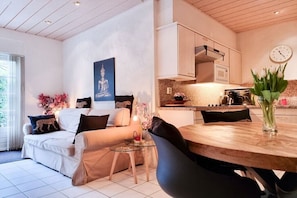 Una sala moderna con un sofá, una mesa de comedor y una cocina al fondo.