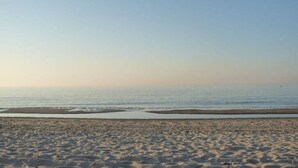 Uma praia com céu claro e mar calmo.