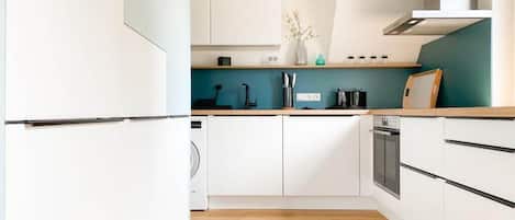 Una cocina moderna con armarios blancos, encimera de madera y horno empotrado.