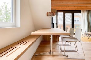 A modern room with a wooden bench, a table, and chairs. - Holiday apartment with 3 bedrooms (Scharbeutz)