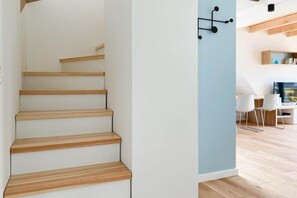 A staircase with wooden steps leading to a room with a light blue accent wall, a desk, and chairs. - Holiday apartment with 3 bedrooms (Scharbeutz)