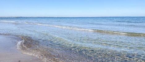 A beach with clear water and a visible shoreline.
