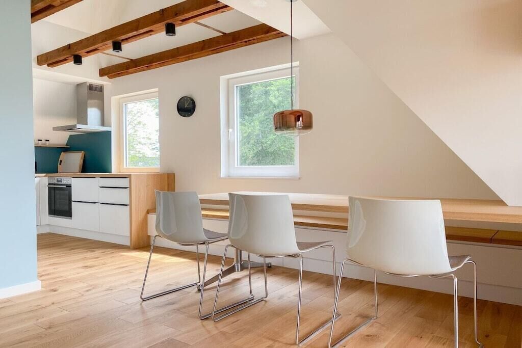 Une cuisine moderne avec des meubles blancs, un four encastré et une fenêtre au-dessus de l’évier.
