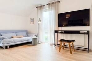 A modern living room with a sofa, a small stool, a table, and a TV mounted on the wall. - Four Seasons||Timmendorfer Strand (Timmendorfer Strand\/Niendorf)