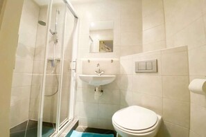 Een badkamer met toilet, wastafel, douche en spiegel.