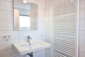 Une salle de bain avec un lavabo blanc, un miroir et un porte-serviettes.