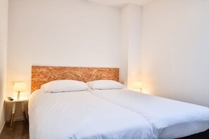 Un lit simple avec une tête de lit en bois dans une chambre d’hôtel.