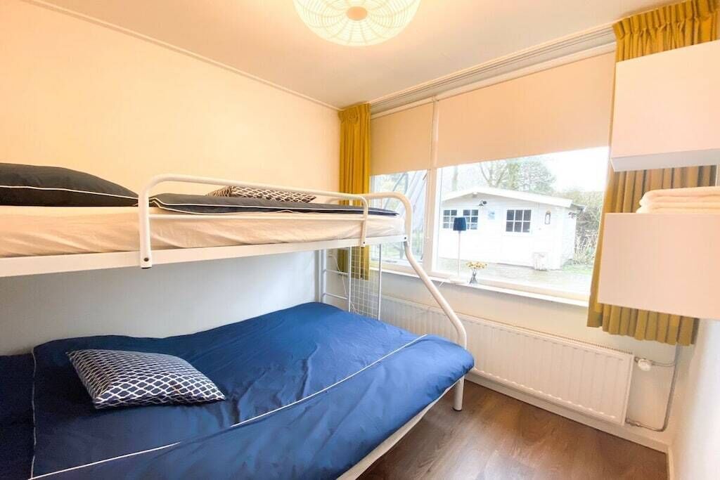 Ein Schlafraum mit Etagenbett, Fenster, Heizkörper und Vorhang.
