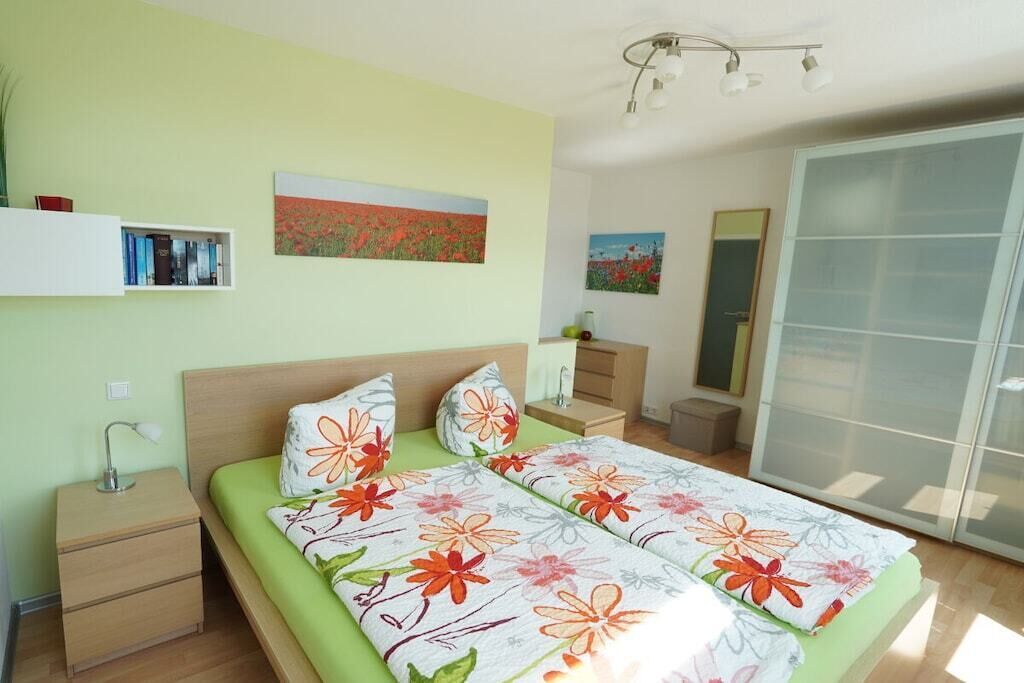 A bedroom with a bed, bedside tables, a wardrobe, and artwork on the walls.