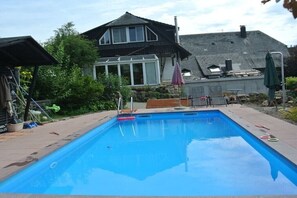 A swimming pool with a house in the background. - Organic farm with 2 bedrooms (Elzach\/Heidburg)