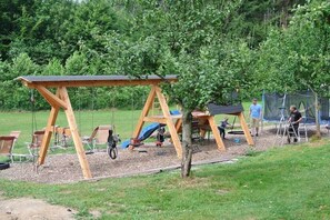 A playground with swings and slides, surrounded by trees and a grassy area. - Organic farm with 2 bedrooms (Elzach\/Heidburg)