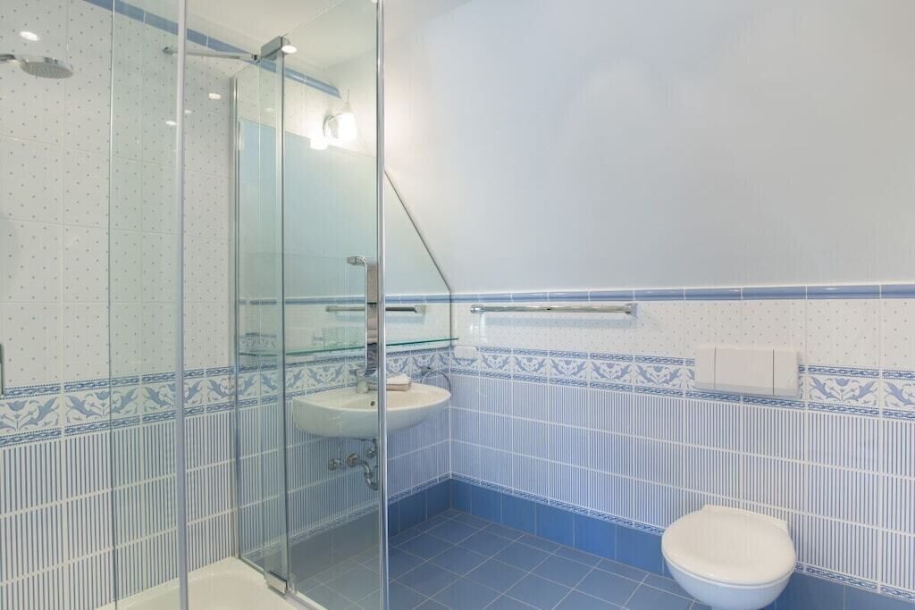 Une salle de bain avec une douche à parois en verre, un lavabo et des toilettes.