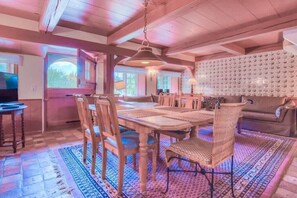 A wooden dining room with a large table and chairs, a patterned rug, and a ceiling with exposed beams. - Friesenhaus Sara (S3) (Wenningstedt)