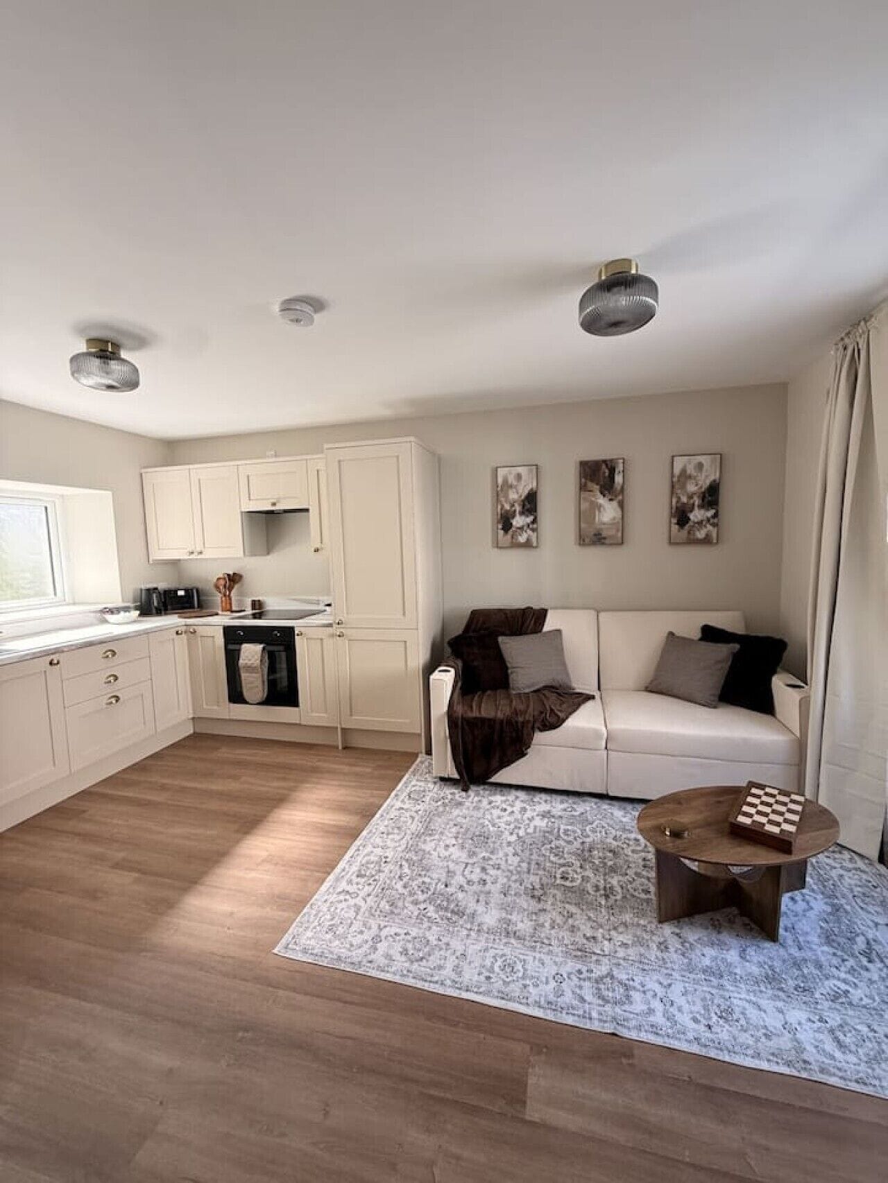 A modern living room with a sofa, a coffee table, and a kitchen area with cabinets and appliances.