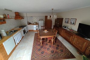 A compact kitchen with a dining table, chairs, a rug, and a TV. - Holiday apartment with 1 bedroom (Friesenhagen)