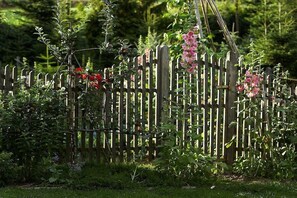 A wooden fence with a garden in the background. - Holiday apartment with 1 bedroom (Friesenhagen)