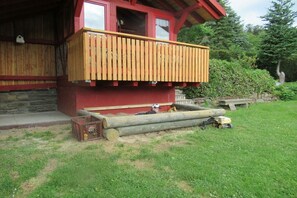 A wooden deck with a red building in the background. - Holiday apartment with 1 bedroom (Friesenhagen)