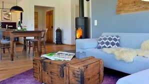 Uma sala de estar moderna com sofá, mesa de centro de madeira, lareira e área de jantar com mesa e cadeiras de madeira.