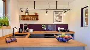 Cozinha moderna com bancada de madeira, eletrodomésticos embutidos e uma fruteira.