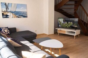 Ein stilvolles Wohnzimmer mit einer Couch, einem Couchtisch und einem Fernseher auf einem Schrank.