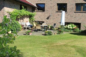 A brick building with a patio area featuring outdoor furniture and a garden. - Holiday apartment with 2 bedrooms (Simmerath-)