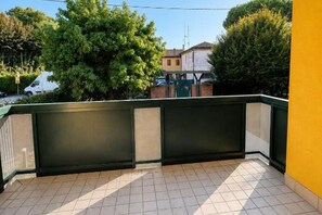 A balcony with a tiled floor, surrounded by a yellow wall and a green railing. - Venice Easy Stay | New Apartment with Parking (Mestre)