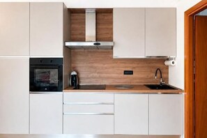 A modern kitchen with a built-in oven, a coffee maker, and a sink. - Venice Easy Stay | New Apartment with Parking (Mestre)